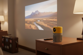 Pocket mini projector on a hotel nightstand projecting a movie onto a wall